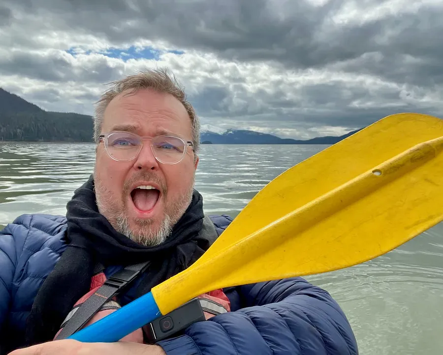 A man hold up a yellow kayak paddle
