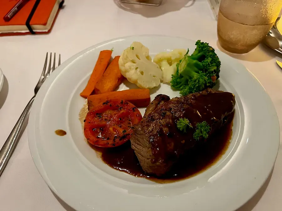 A steak and vegetables served on a white plate