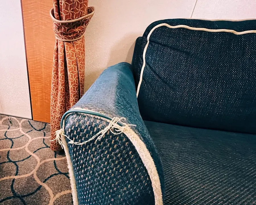 A navy blue sofa arm showing fraying along the edges