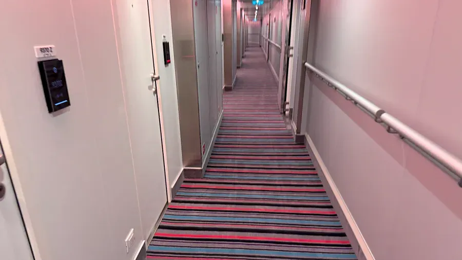 Colourful striped carpet in a cabin corridor on Virgin Voyages Scarlet Lady