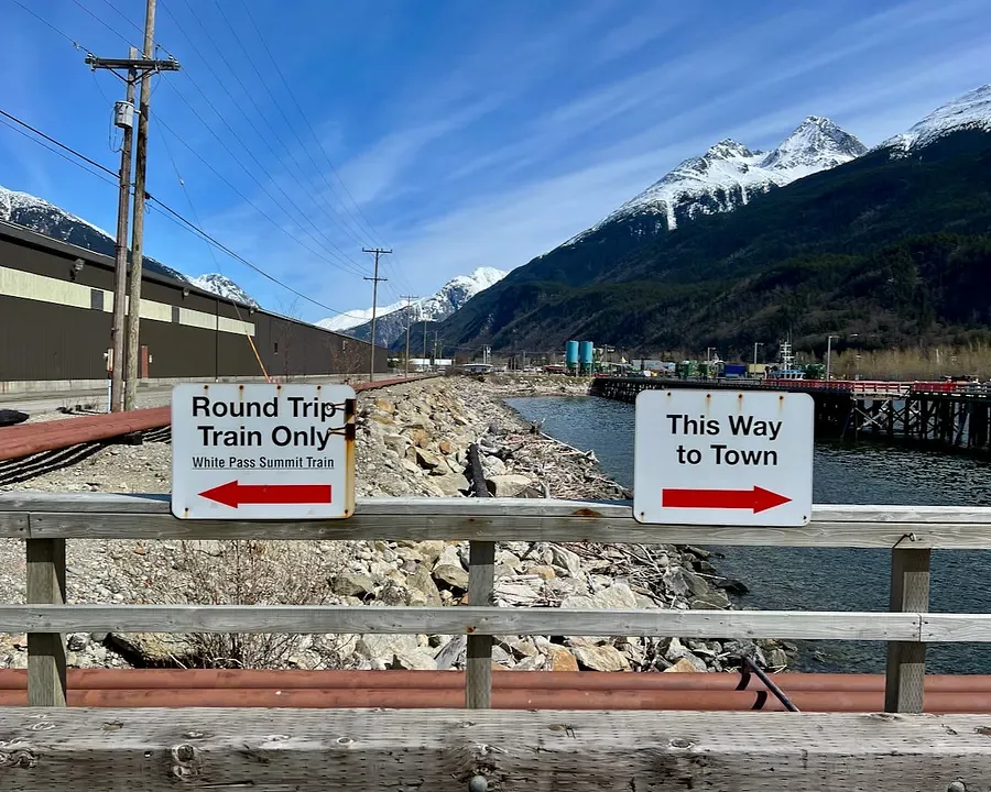 Two signs on a bridge in Skagway, one to White Pass railcards and the other to downtown