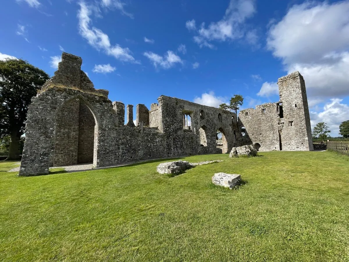The cloister arches at Bective Abbey with the defensive tower beyond, County Meath