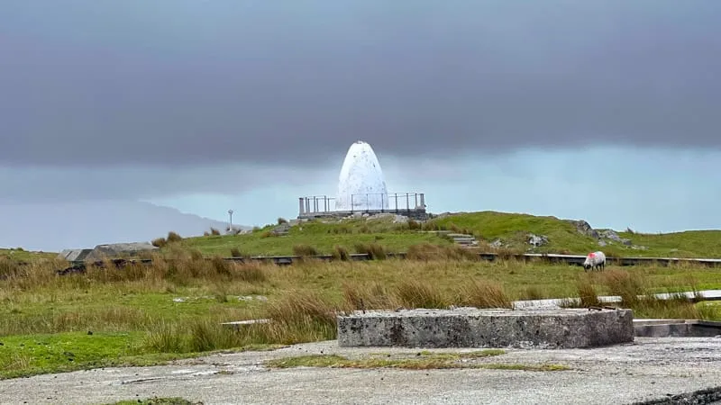 The white Alcock and Brown memorial cairn at Derrygimlagh with sheep grazing on the bog