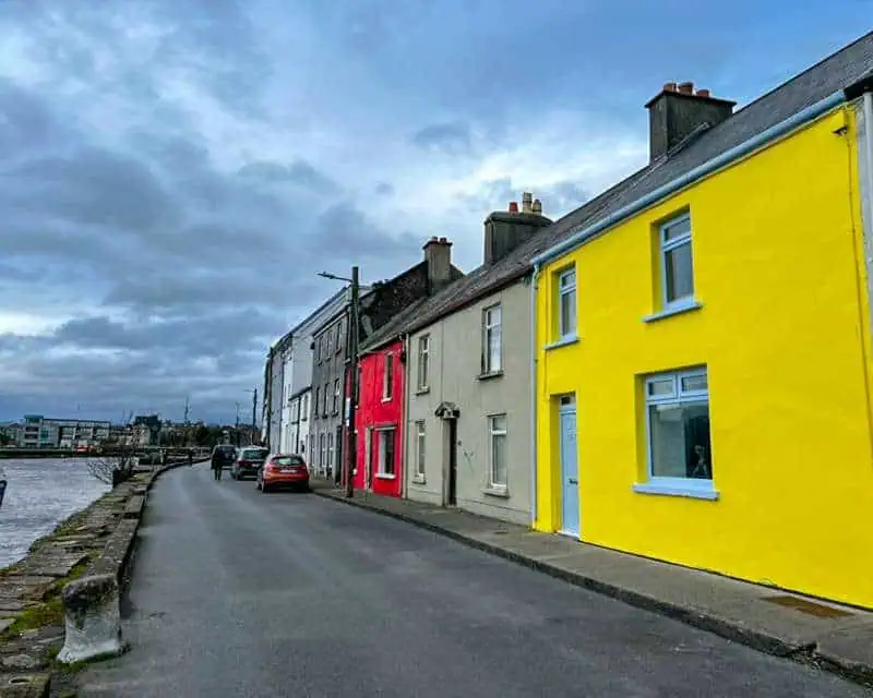 Street scene in Galway with a bright yellow terraced house in the foreground