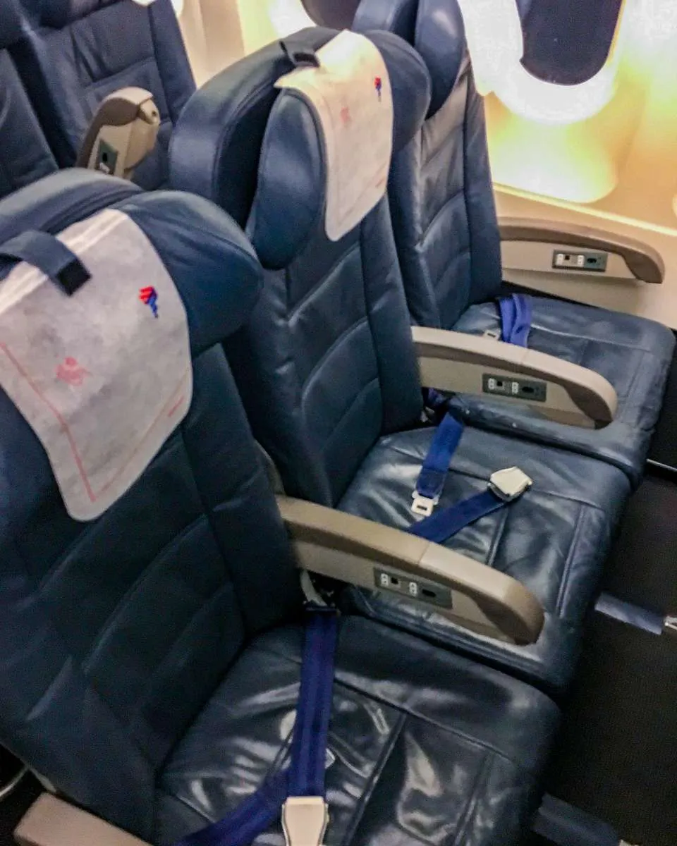Blue leather plane seats on Latam Economy showing signs of wear