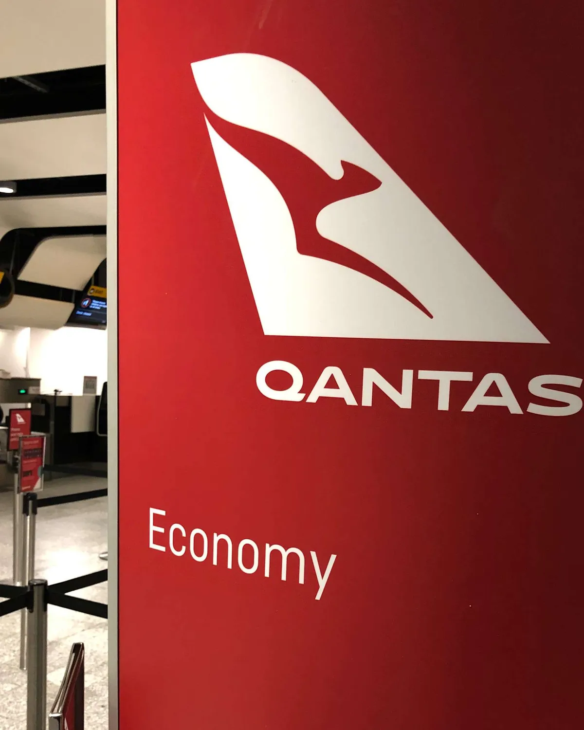 Qantas QF10 Flight Review - The red signage of Qantas showing the Economy check-in area