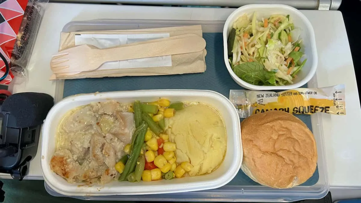 A meal served on Air New Zealand consisting of a chicken and potato dish that looks a little grey. 
