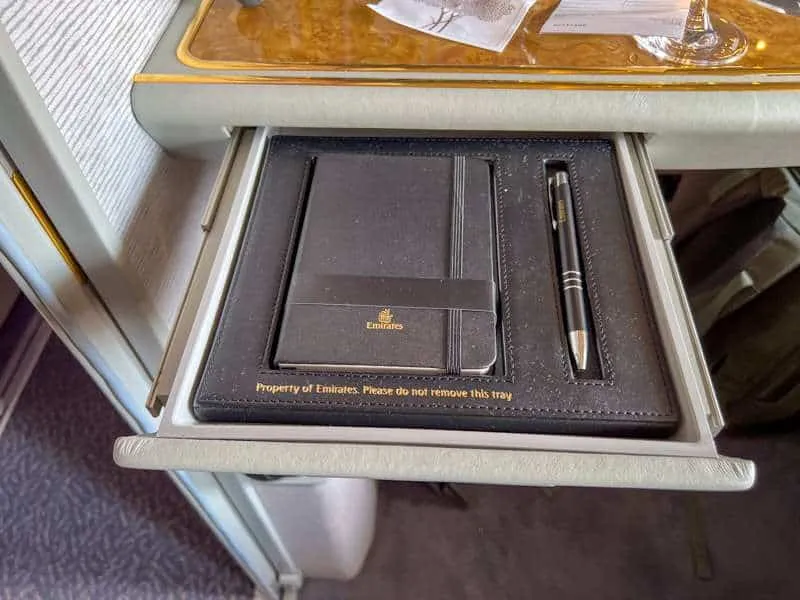 A black journal and pen is in its own tray in an Emirates first class seat
