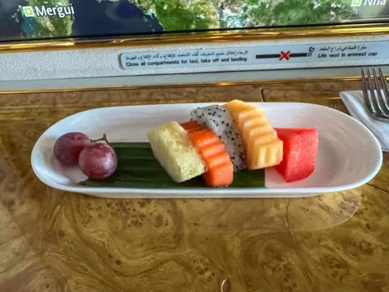 A snack of freshly cut fruit including pineapple and dragonfruit served in Emirates first class cabin. 