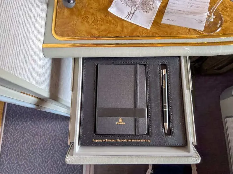 A slide out drawer showing a free Emirates journal and pen in the first class suite 