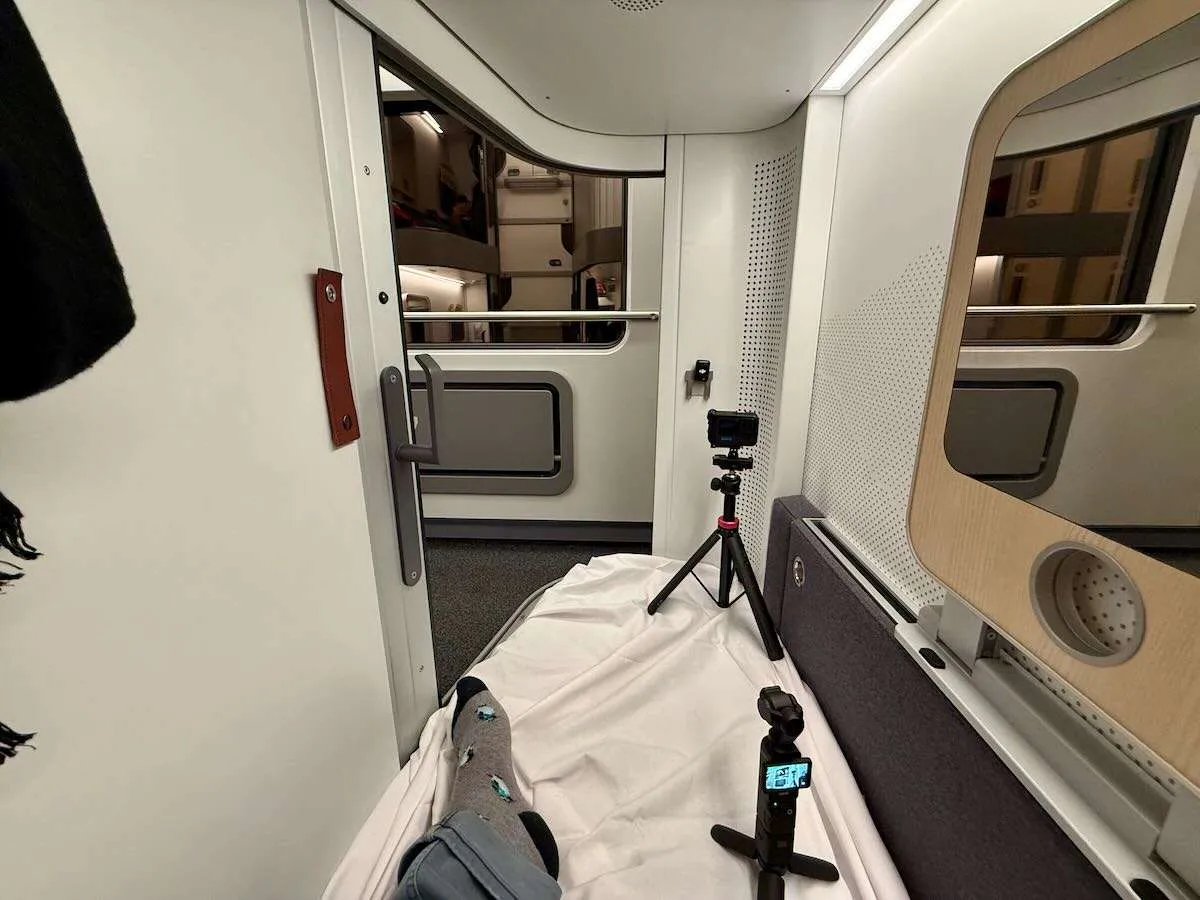 A man's feet on the bed of a mini cabin on Nightjet