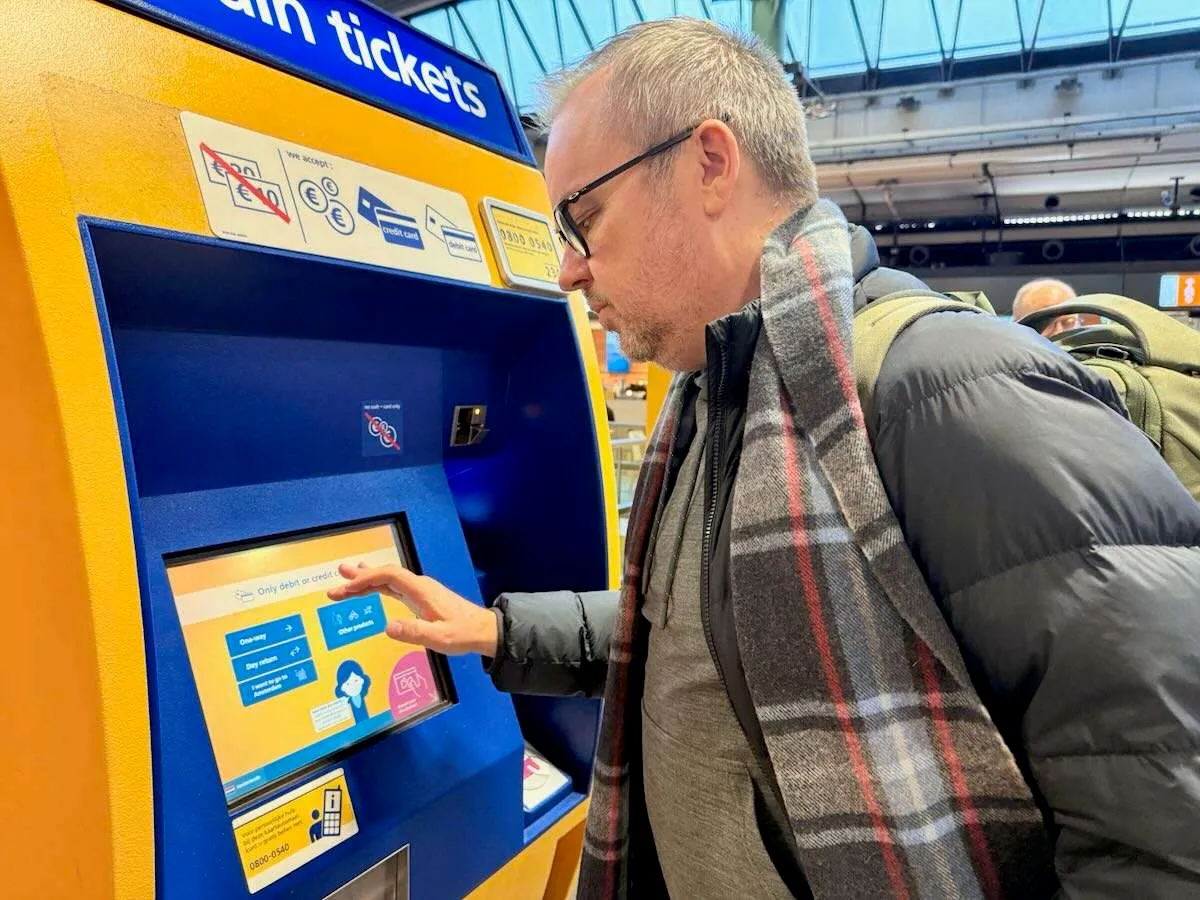 Patrick Hughes buying a train ticket at Schiphol Airport