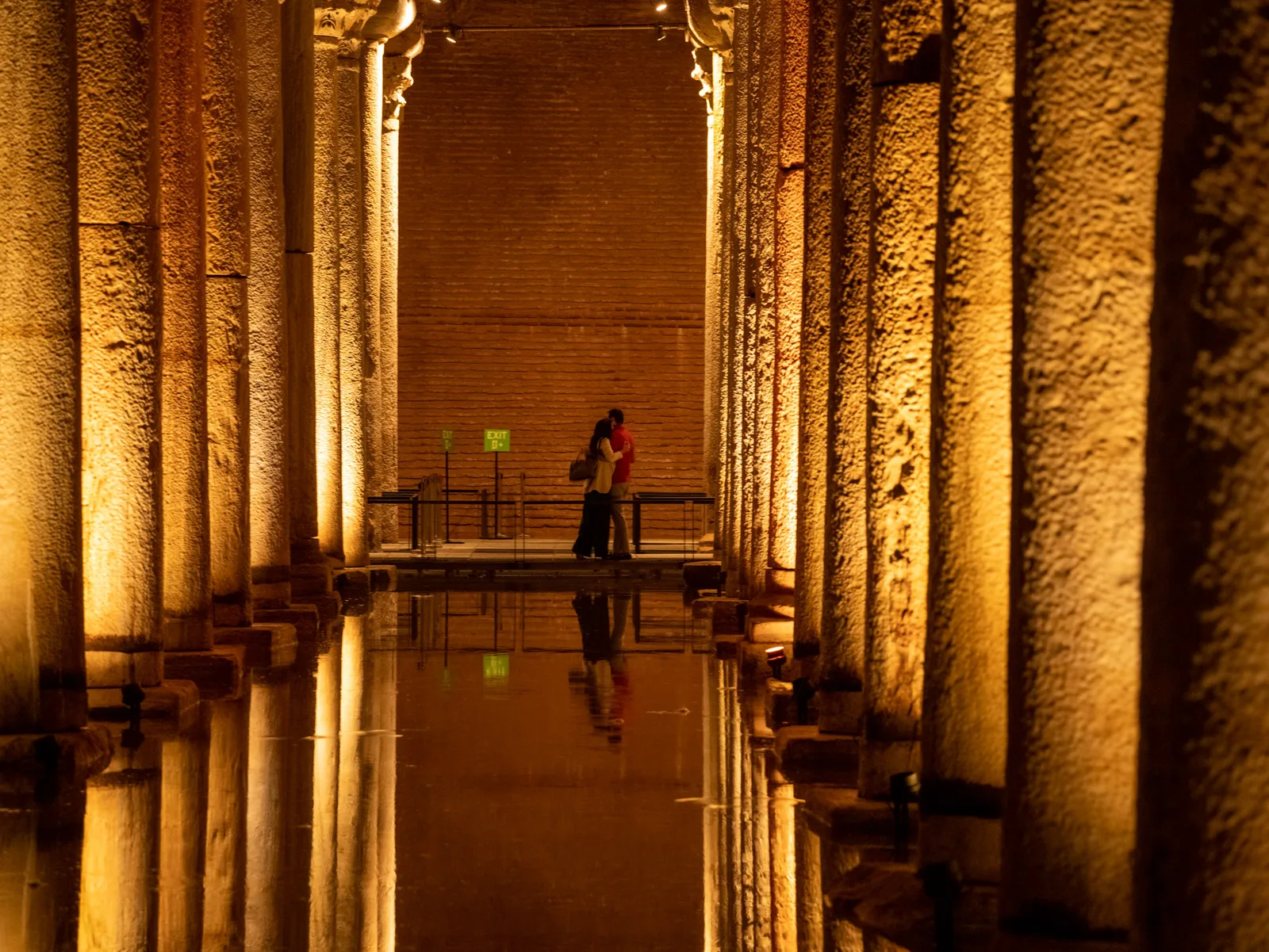 A raised walkway running between lit columns down the length of the Basilica Cistern, reflected in the water