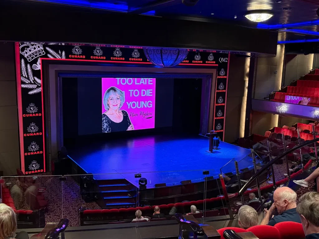 Theater stage on Cunard cruise ship showing 'Too Late to Die Young' presentation with Kate Minton