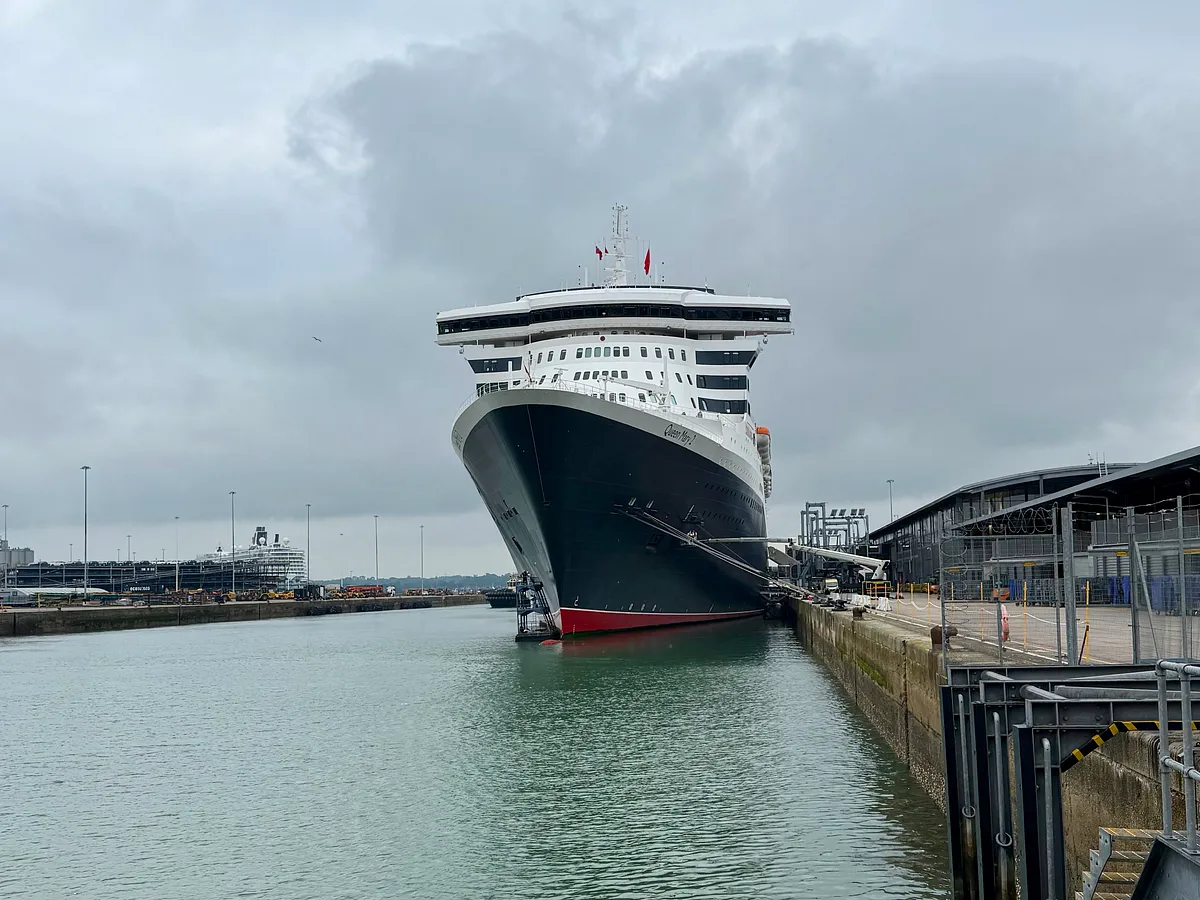 Queen Mary 2 cruise ship docked at port terminal under overcast skies