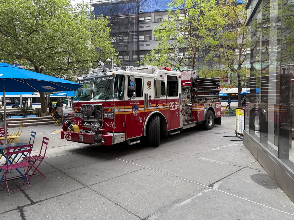 FDNY Engine 226 fire truck parked on a New York City sidewalk near outdoor cafe seating