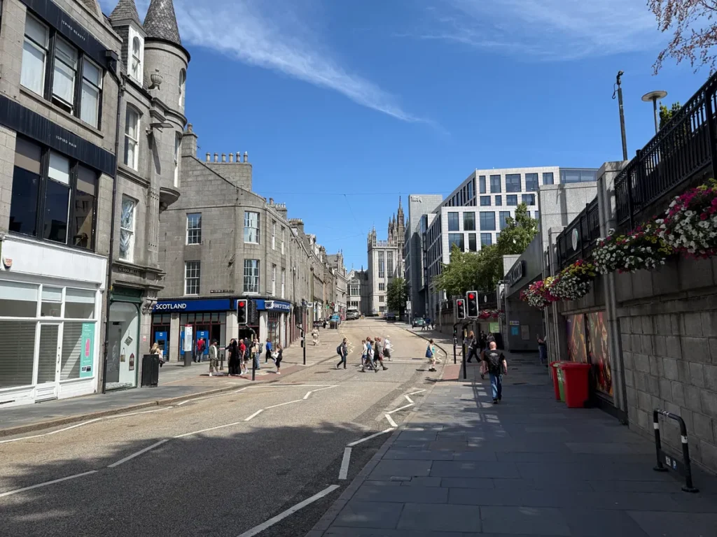 Pedestrian street in Aberdeen city center with granite buildings and church spire