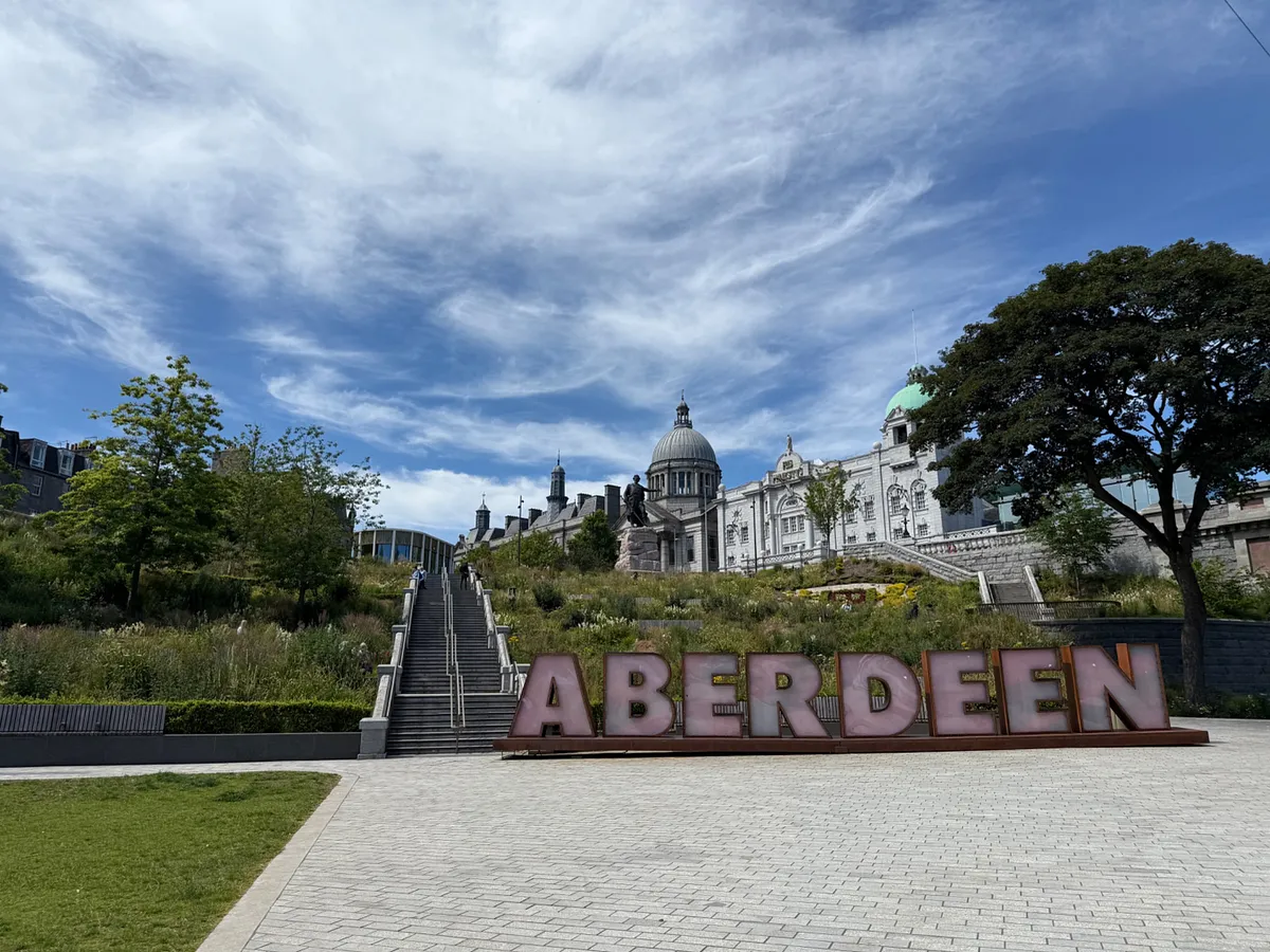Aberdeen sign with stairs leading to historic buildings and green dome in Aberdeen, Scotland