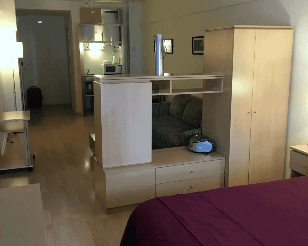 Interior of an aparthotel room showing the edge of a bed, and a wardrobe room divider prominently in shot.