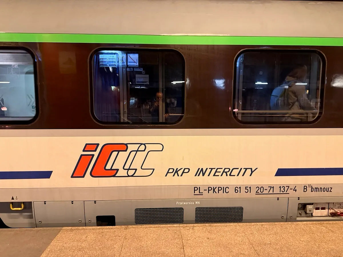 PKP Intercity train carriage with distinctive orange and cream livery at a Polish railway station