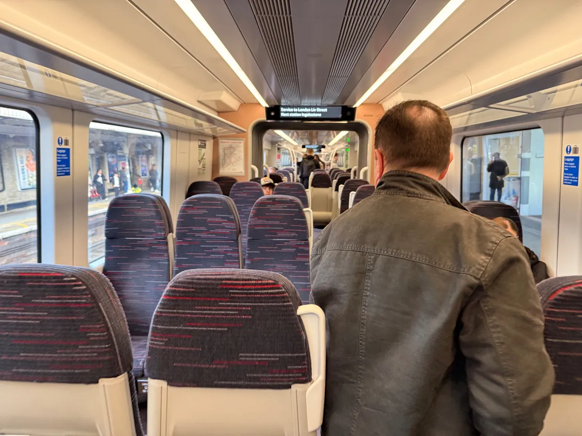 Interior of Greater Anglia train carriage with striped seats and passengers en route to London Liverpool Street