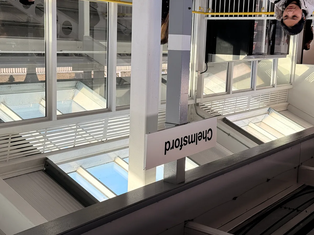 Platform signage showing Chelmsford station name on white modern shelter structure